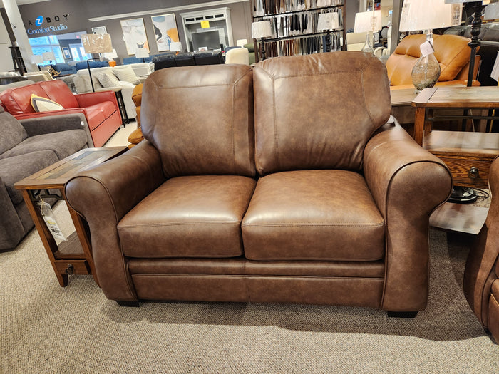 The Orangeville Leather Loveseat by Leather Craft is showcased in a Toronto showroom among sofas and tables.