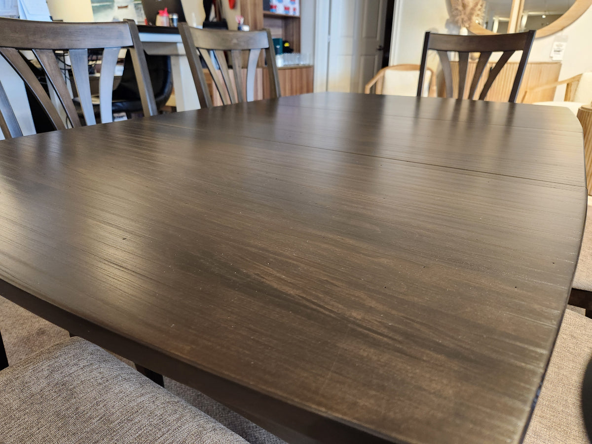 Rustic charm: Handstone Parker 7pc set—dark wood table with smooth top and cushioned chairs in a bright space.