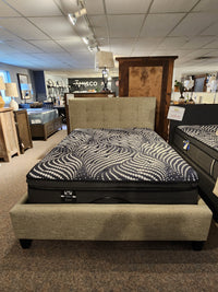 The Queen Heaven Upholstered Bedframe by Julien Beaudoin with a tufted headboard is displayed among wooden furniture.