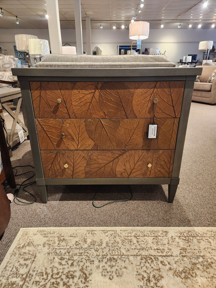 The Crestview Collection Arbor Three Drawer Chest in sage green with leaf pattern is displayed in the showroom.
