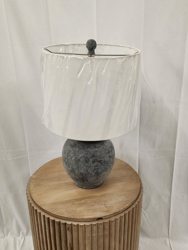 The 862D0 Anza Table Lamp by Pacific Coast, with a drum shade, is displayed on a wooden pedestal against a white backdrop.