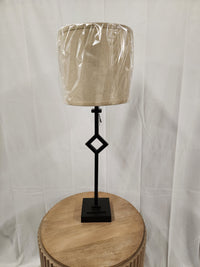 The Pacific Coast 519V0 Audrey Table Lamp with a neutral drum shade sits on a round wooden table.