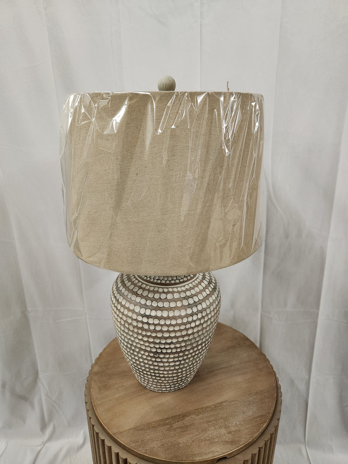 Pacific Coast 87-10158-21 table lamp with a patterned base and fabric shade sits on a round table.