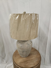 Pacific Coast 87-10158-21 table lamp with a patterned base and fabric shade sits on a round table.
