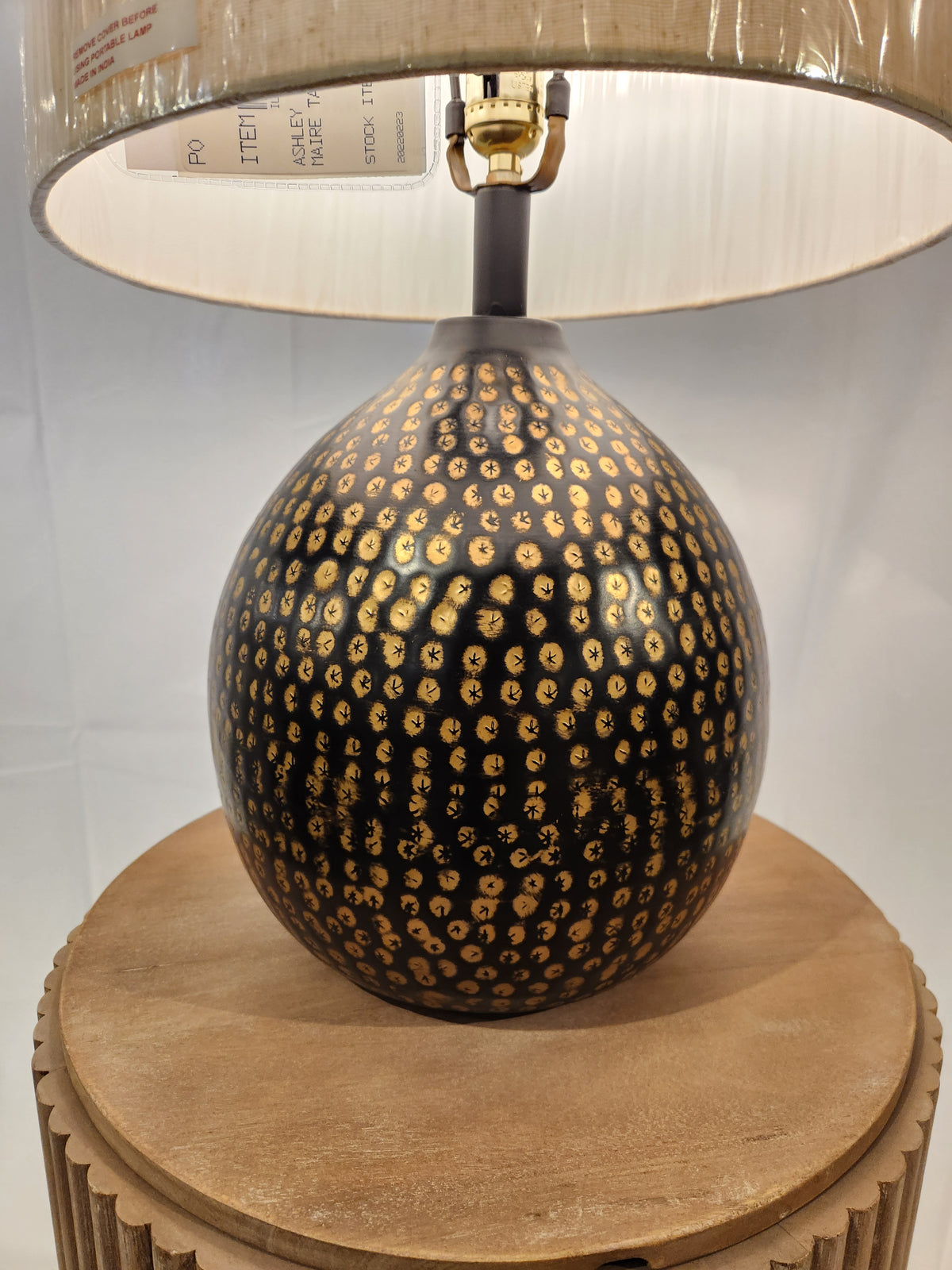 The Ashley Maire Table Lamp features a black and gold base and beige shade—ideal for urban industrial style.