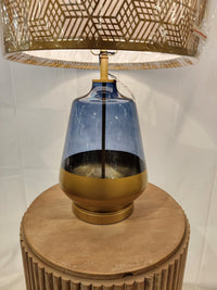The Pacific Coast 87-08448-51 Taurus Table Lamp has a blue and gold glass base, perfect for your round wooden table.