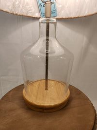 Pacific Coast 37M69 Taylor Table Lamp with glass and wood base, ideal for coastal homes, on a round brown table.