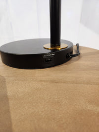 Pacific Coast 96J17 Holmes Table Lamp in matte black with USB port (5V DC, 2A max) on a wooden surface.
