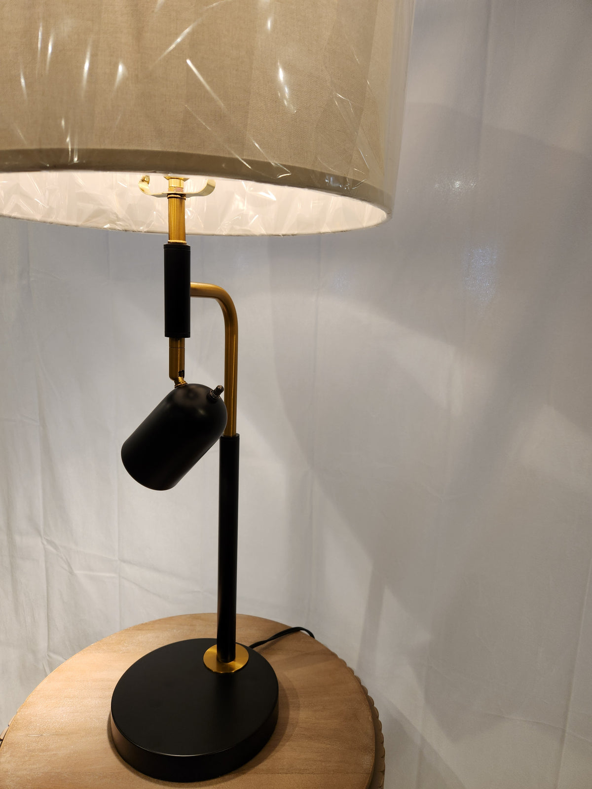 The 96J17 Holmes Table Lamp by Pacific Coast with a black and brass base sits on a round wooden table.