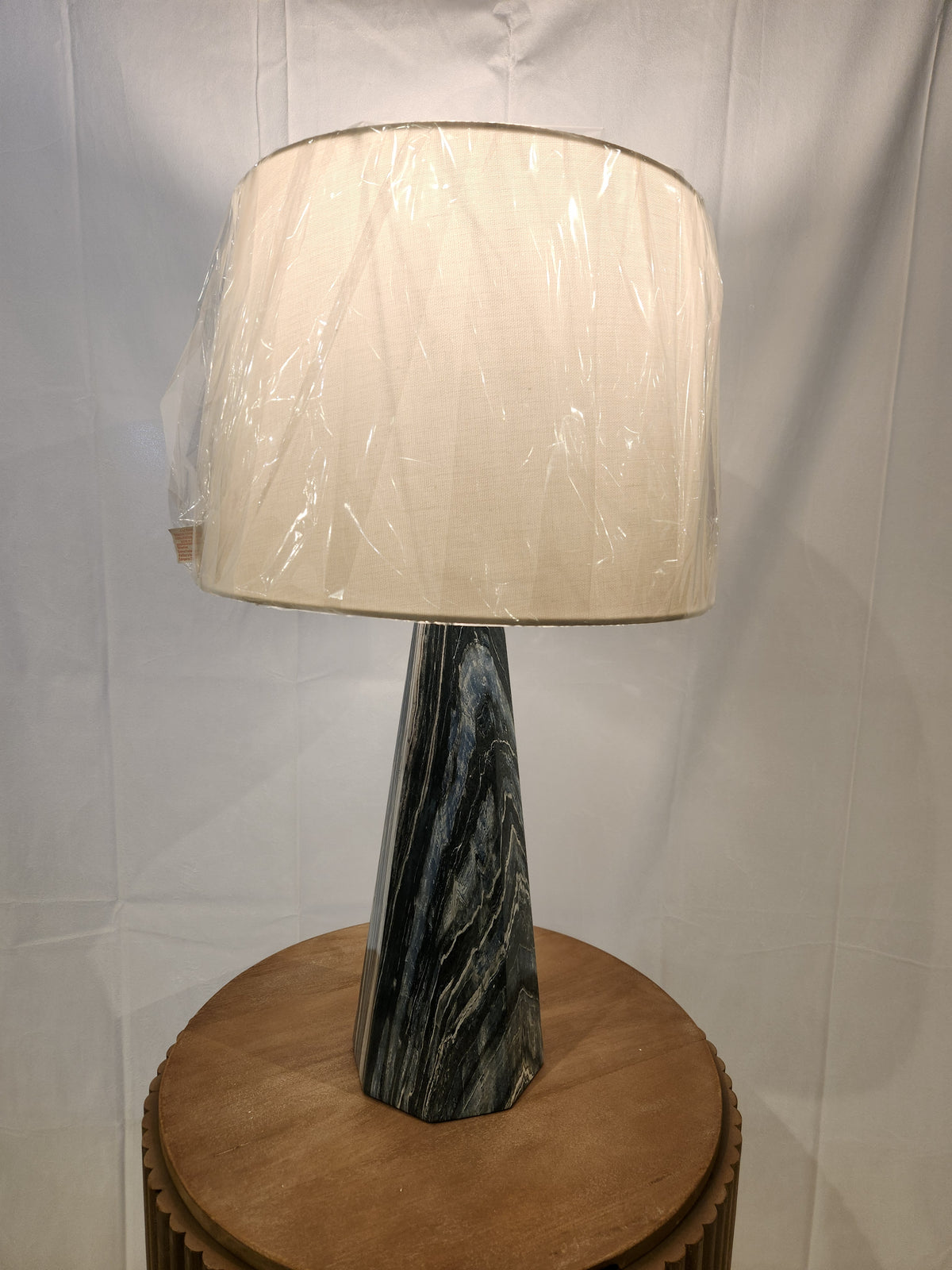 The Pacific Coast Bluestone set of 2 table lamps with linen drum shades sits on a round wooden table.