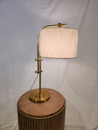 Ashley Baronvale L206053 table lamp with adjustable arm and white drum shade on a round wooden side table.