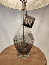 Pacific Coast Sparrow set of 2 table lamps with clear glass, metallic accents, and linen drum shades on a wooden surface.