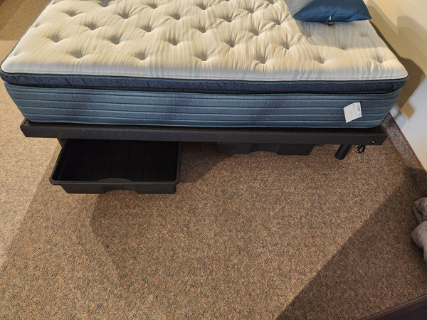 A blue and white mattress on a Julien Beaudoin Platform Bed Rail Kit with open black storage drawer on carpeted floor.