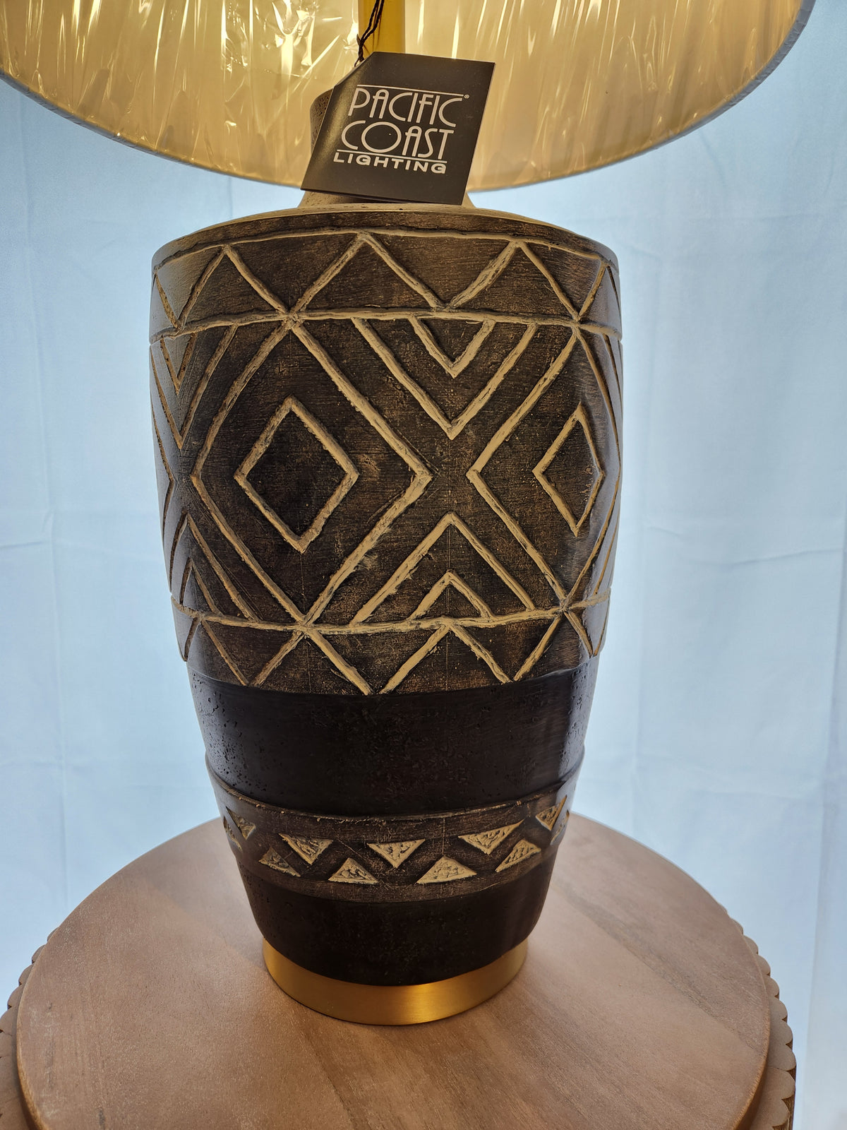 73M52 Mesa Table Lamp by Pacific Coast with ethnic patterns sits on a round wooden surface.