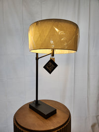 Pacific Coast 74G04 HUGO Modern Desk Lamp with beige shade, partially wrapped, sits on a round table; dimensions listed.