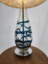 The Pacific Coast 87-6910-23 Indigo Blue Table Lamp adds a modern touch and soft glow with its blue glass swirls.