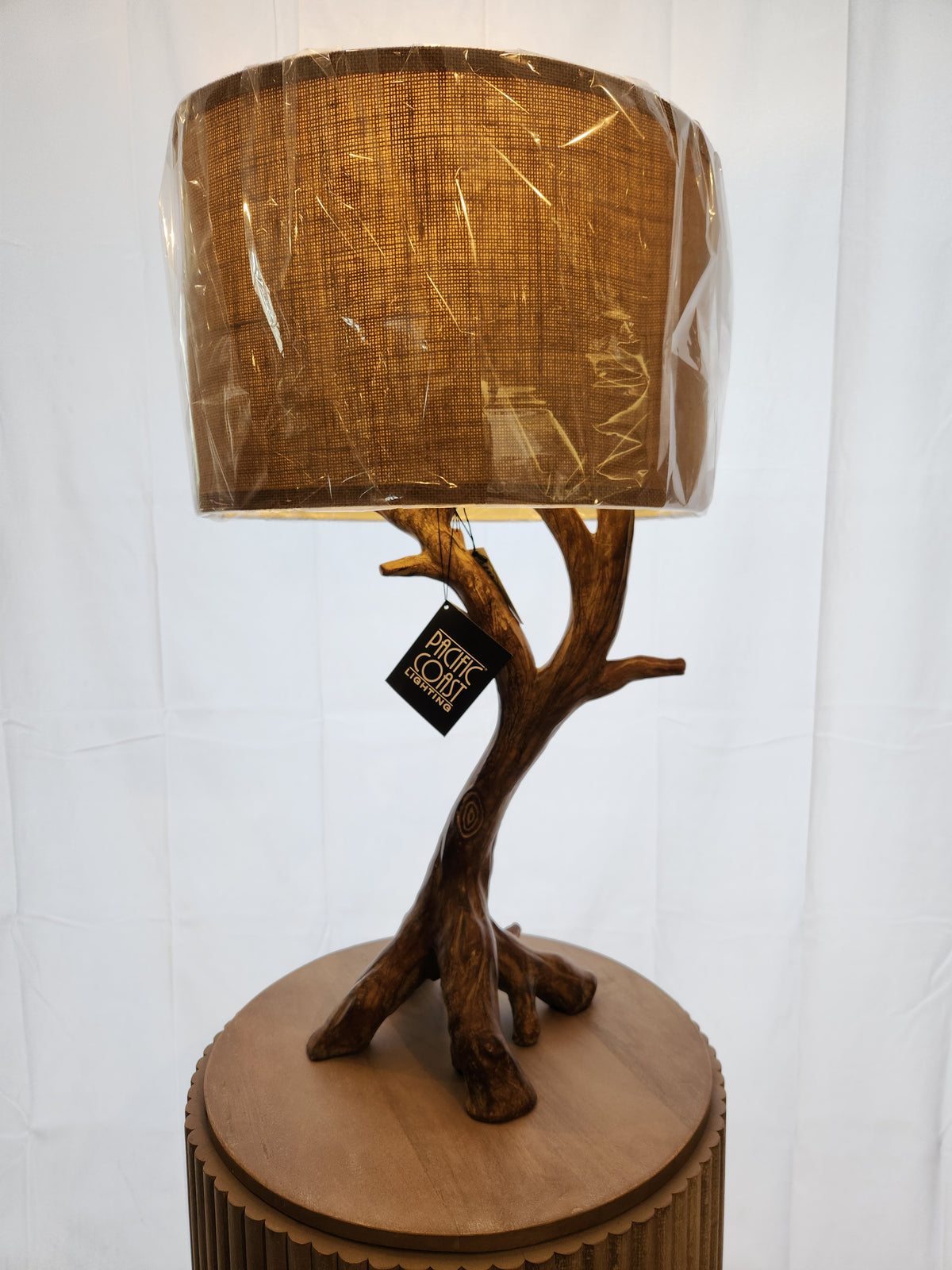 Pacific Coast 87-8036-48 Beachwood Table Lamp with tree-branch base and brown burlap shade on wood stand.