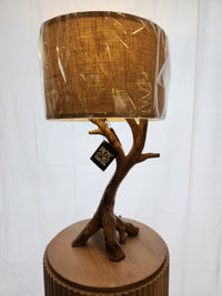 Pacific Coast 87-8036-48 Beachwood Table Lamp with tree-branch base and brown burlap shade on wood stand.