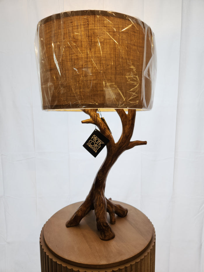 Pacific Coast 87-8036-48 Beachwood Table Lamp with tree-branch base and brown burlap shade on wood stand.