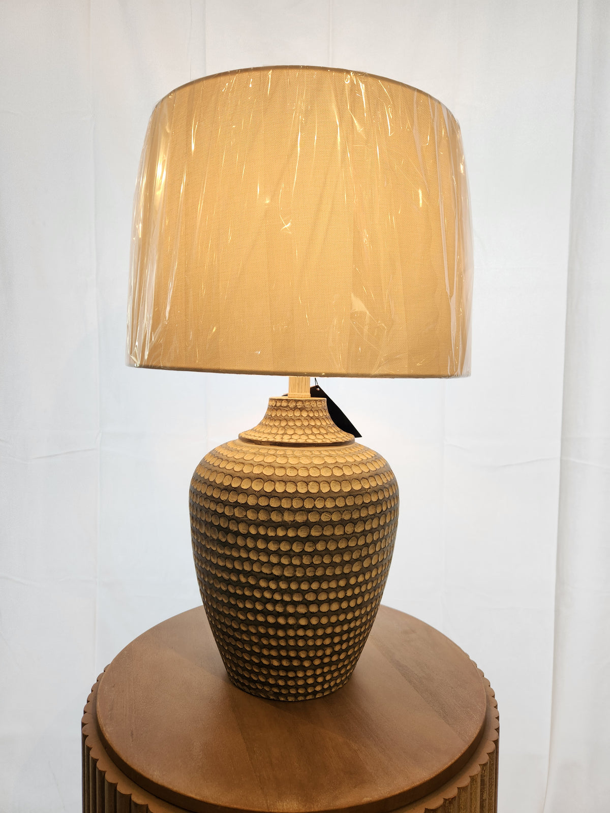 The Pacific Coast 767H1 Alese Table Lamp adds modern sophistication with its textured ceramic base on a round table.