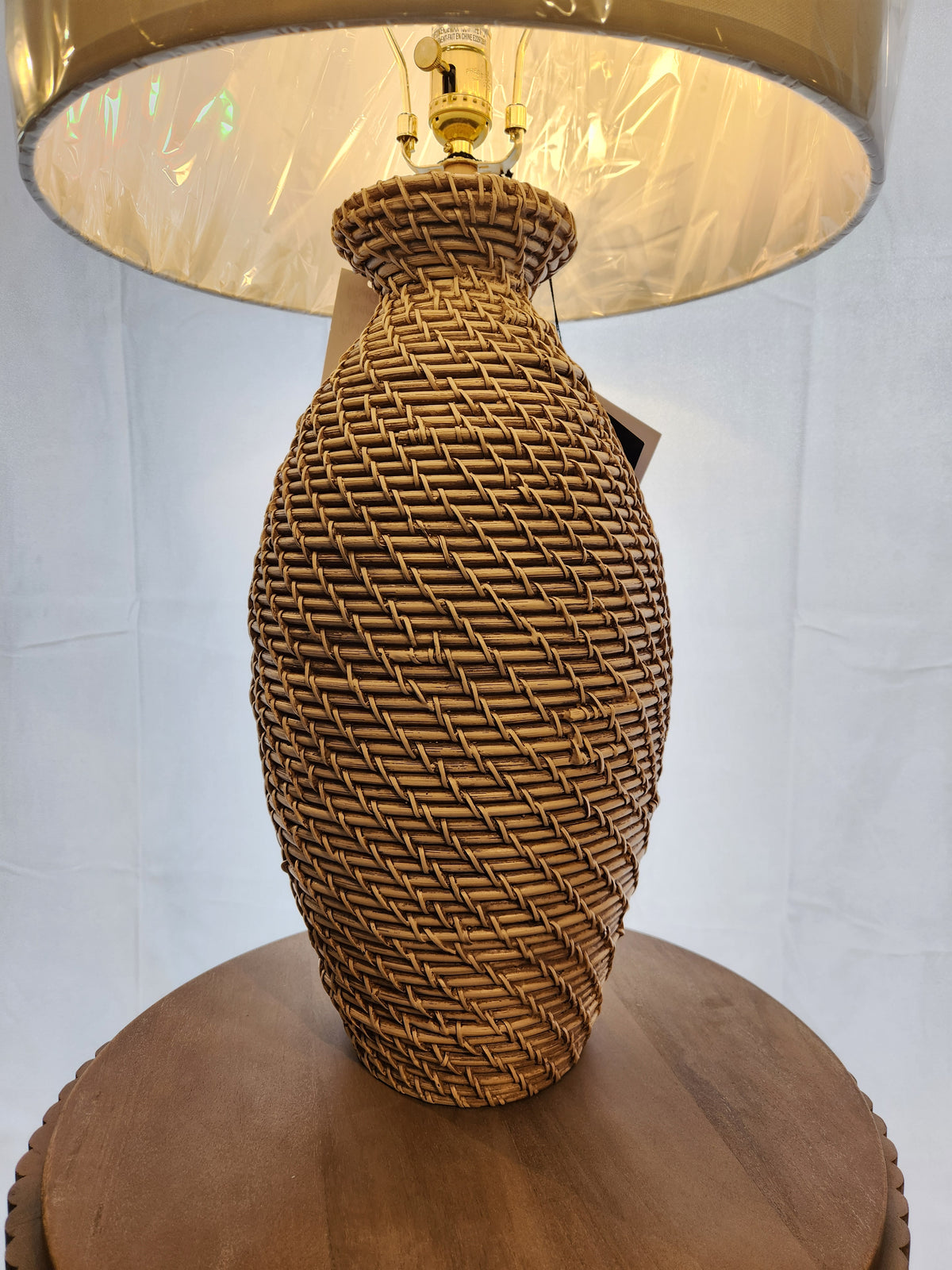 A Pacific Coast 90V98 Finley Table Lamp with a linen shade rests on a round wooden surface.