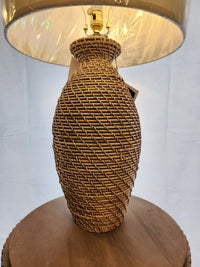 A Pacific Coast 90V98 Finley Table Lamp with a linen shade rests on a round wooden surface.
