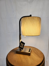 The 902c0 Elton Table Lamp by Pacific Coast, with a linen shade and black frame, sits on the wooden table.