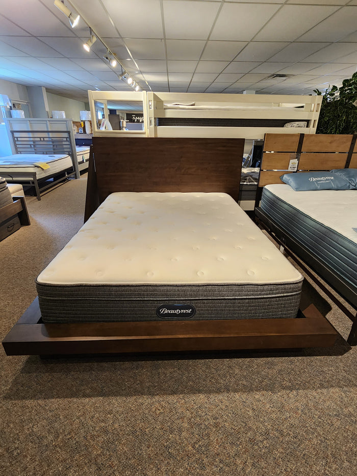 A Universal M2015 Queen Bed Frame with a Beautyrest queen mattress displayed in a showroom among other beds.
