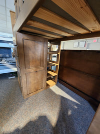 Crate B43200 Versa Loft Bed in Southern Yellow Pine, with shelves and cabinets, shown on carpet in showroom.