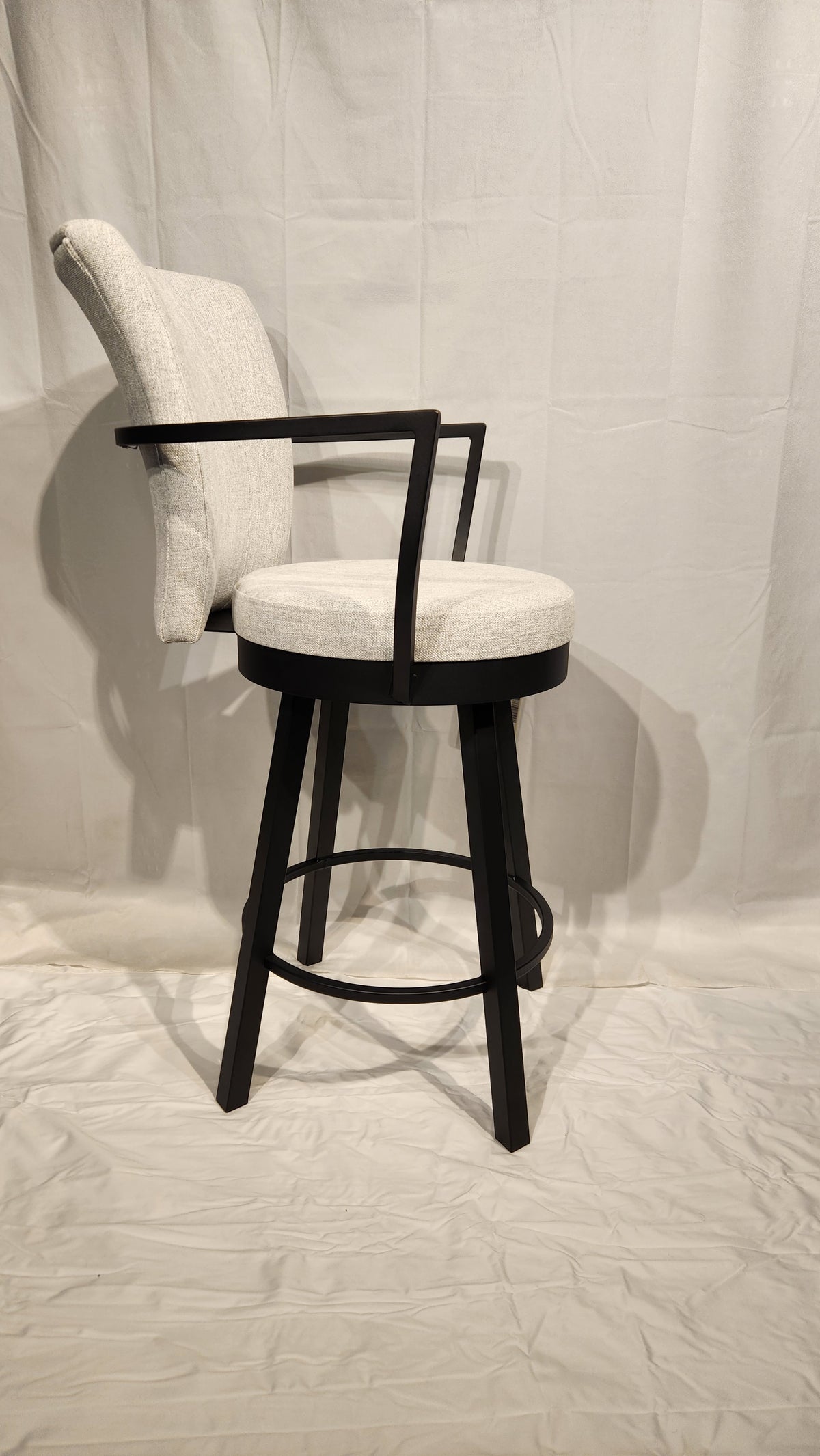 The Amisco Cardin Counter Height Bar Stool features a modern light gray upholstered seat, antiqued black frame, backrest, and footrest.