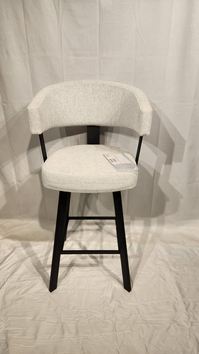 The Amisco Grissom Bar Stool features a curved backrest, black legs, and light gray upholstery on a white background.