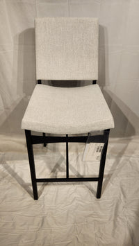 The Amisco Kendra gray bar stool, with a metal frame, stands on a white background with a tag attached to the seat.