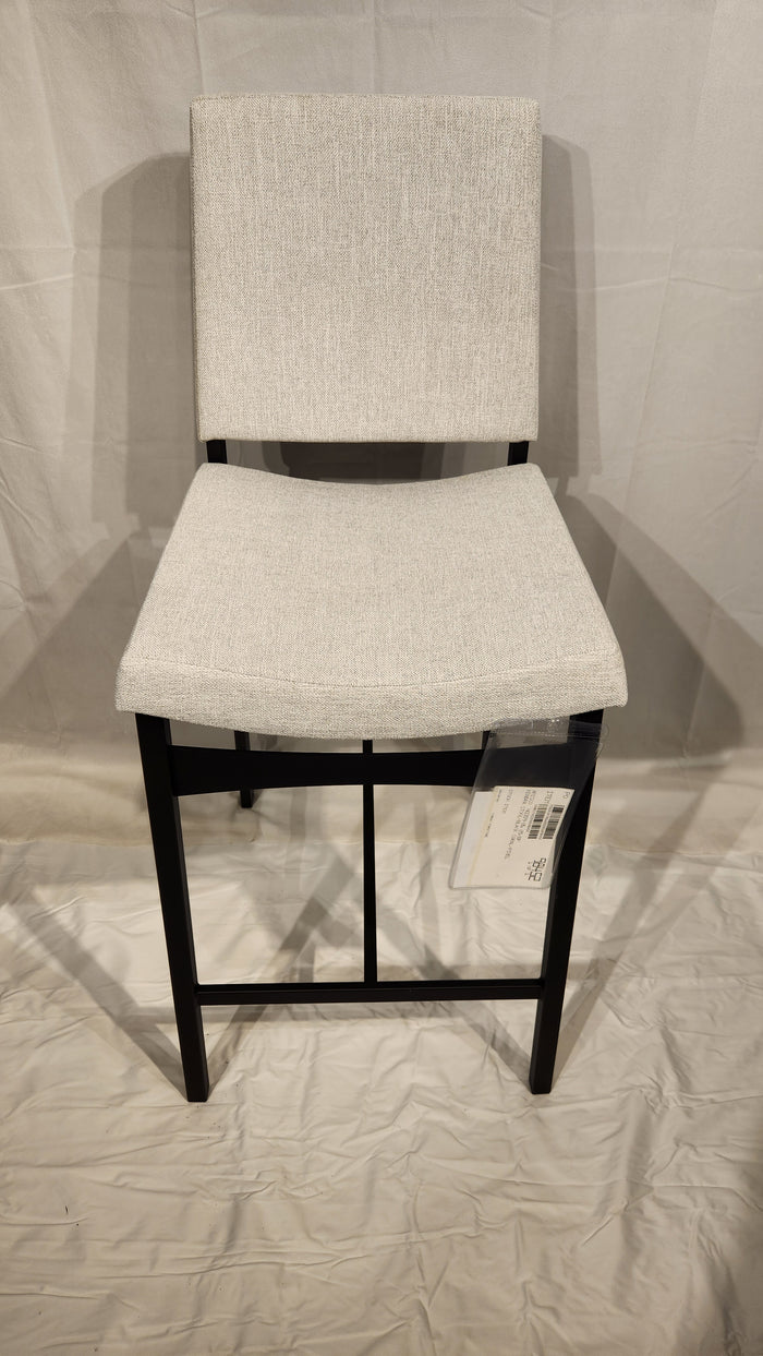 The Amisco Kendra gray bar stool, with a metal frame, stands on a white background with a tag attached to the seat.