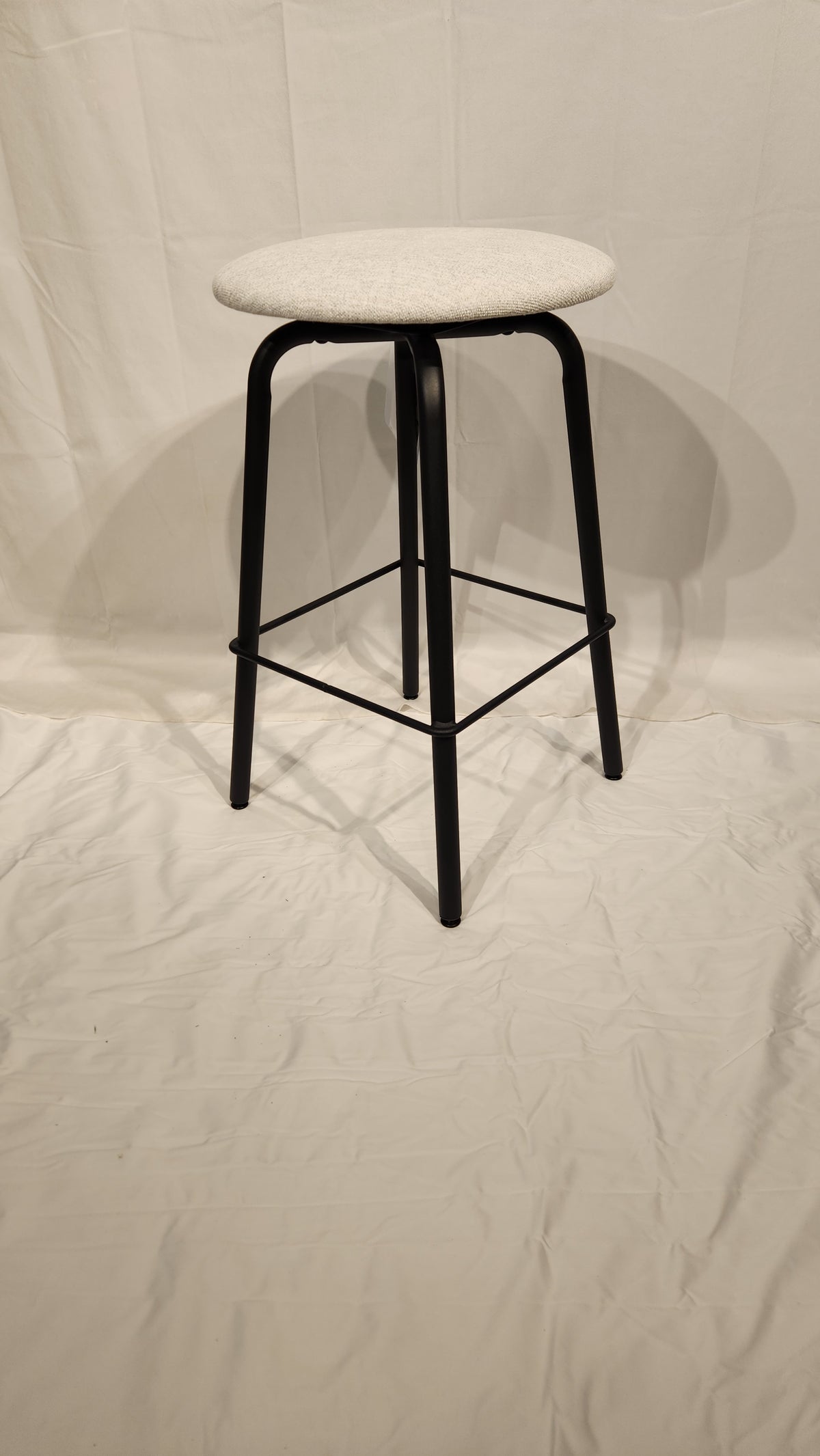 The Amisco Button Counter Height Swivel Stool features light gray upholstery and black metal legs on a white backdrop.