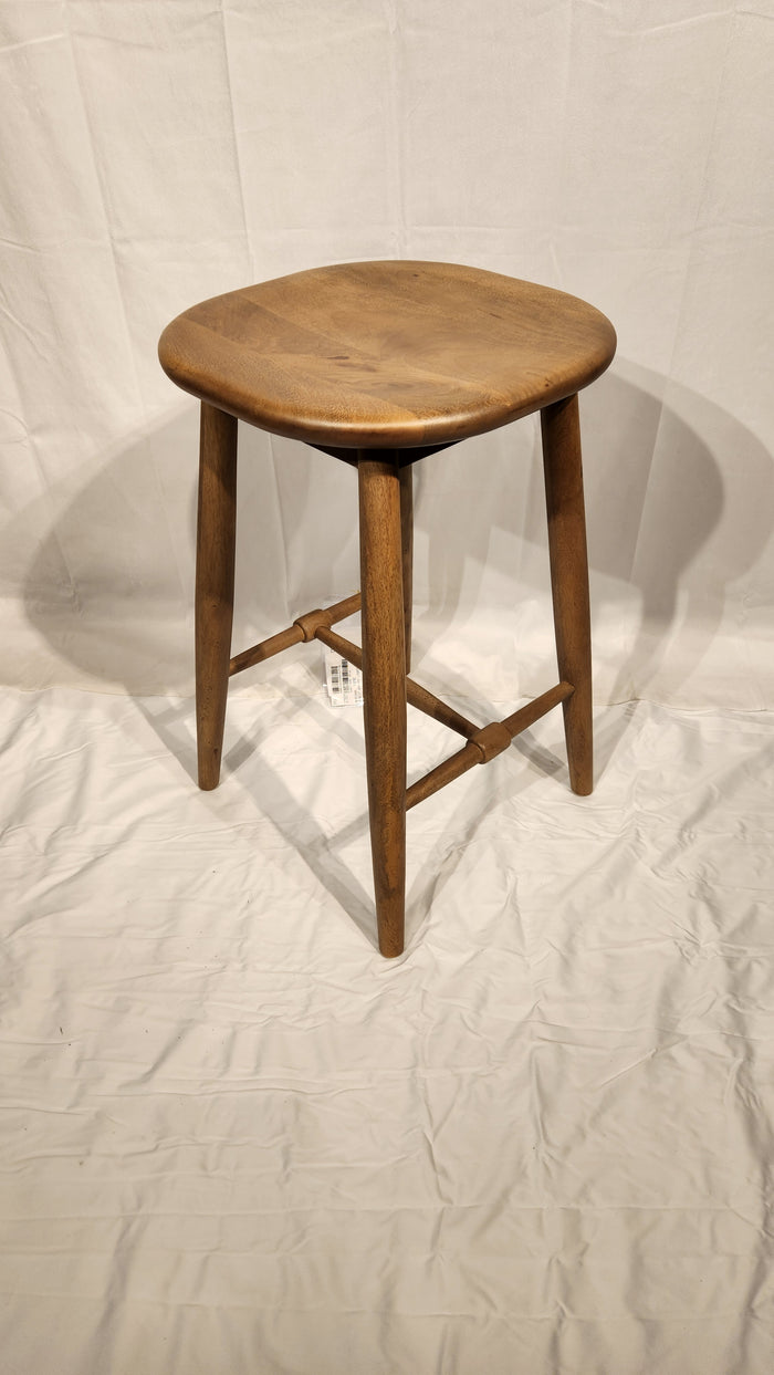 The Ernest Counter Height Bar Stool by Mercana, with a round mango wood seat, stands on wrinkled white fabric.