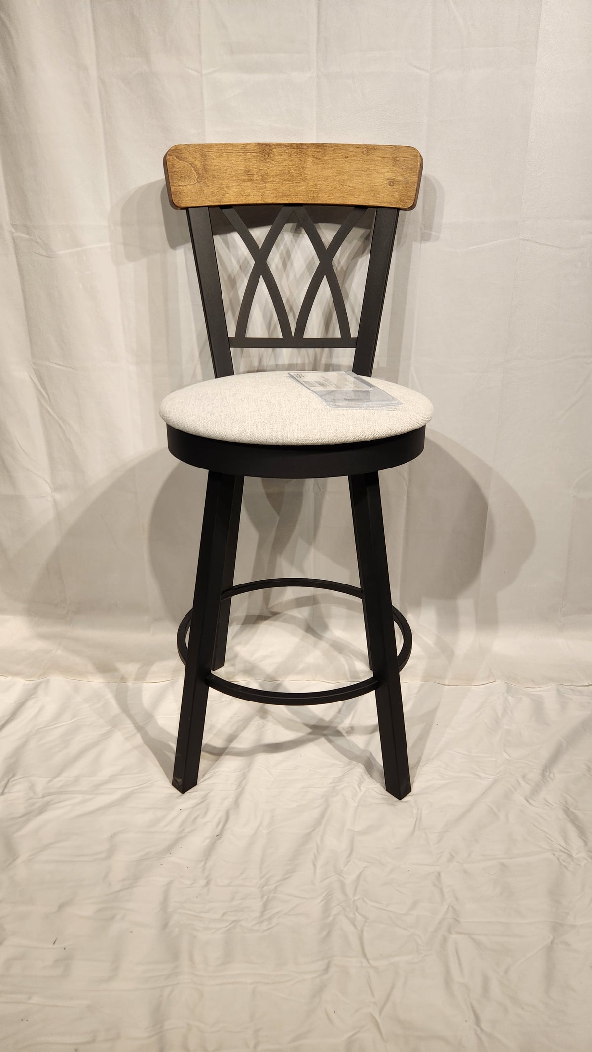 The Amisco Brittany Swivel Bar Stool features a cushioned seat, curved back, and black metal legs with vintage finishes.