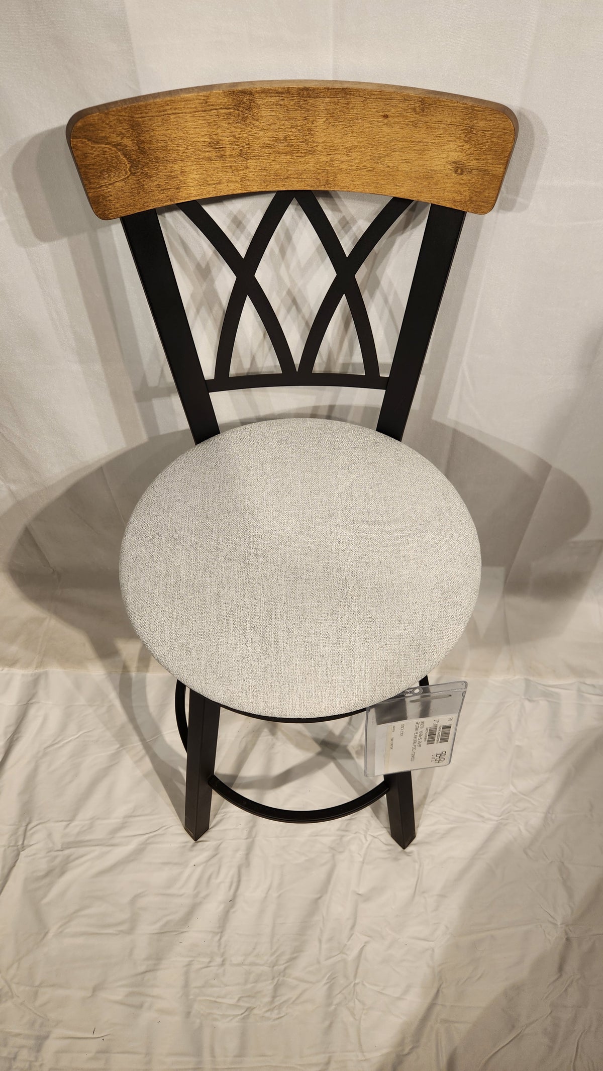The Amisco Brittany Counter Height Swivel Bar Stool features a light gray cushioned seat and vintage-style finishes.