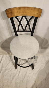 The Amisco Brittany Counter Height Swivel Bar Stool features a light gray cushioned seat and vintage-style finishes.