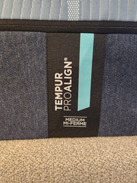 Close-up of a Pro Align 2.0 - Medium label by Tempur-pedic, with blue/black fabric and TEMPUR-APR+ for pressure relief.