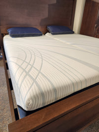 A wooden bed frame with two blue pillows and a Tempur-pedic Align - Soft mattress for pressure-relieving comfort.