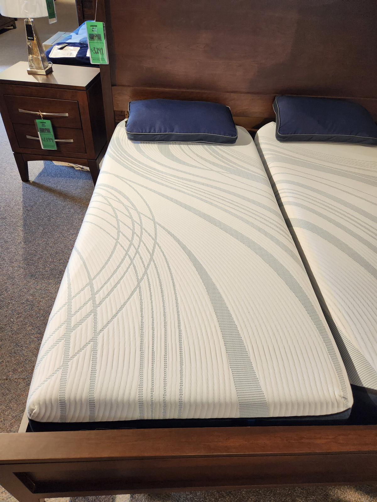 Two Tempur-pedic Align - Soft twin mattresses with blue pillows on a wooden bed frame in a showroom.