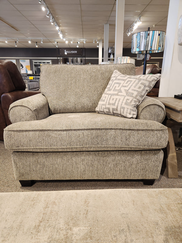 The 2285 Chair and a Half by Decor-rest, featuring gray upholstery with solid wood construction and a patterned cushion, is showcased in a furniture showroom under bright overhead lighting. Experience the comfort of this seat, expertly crafted for those who appreciate Canadian-made quality.
