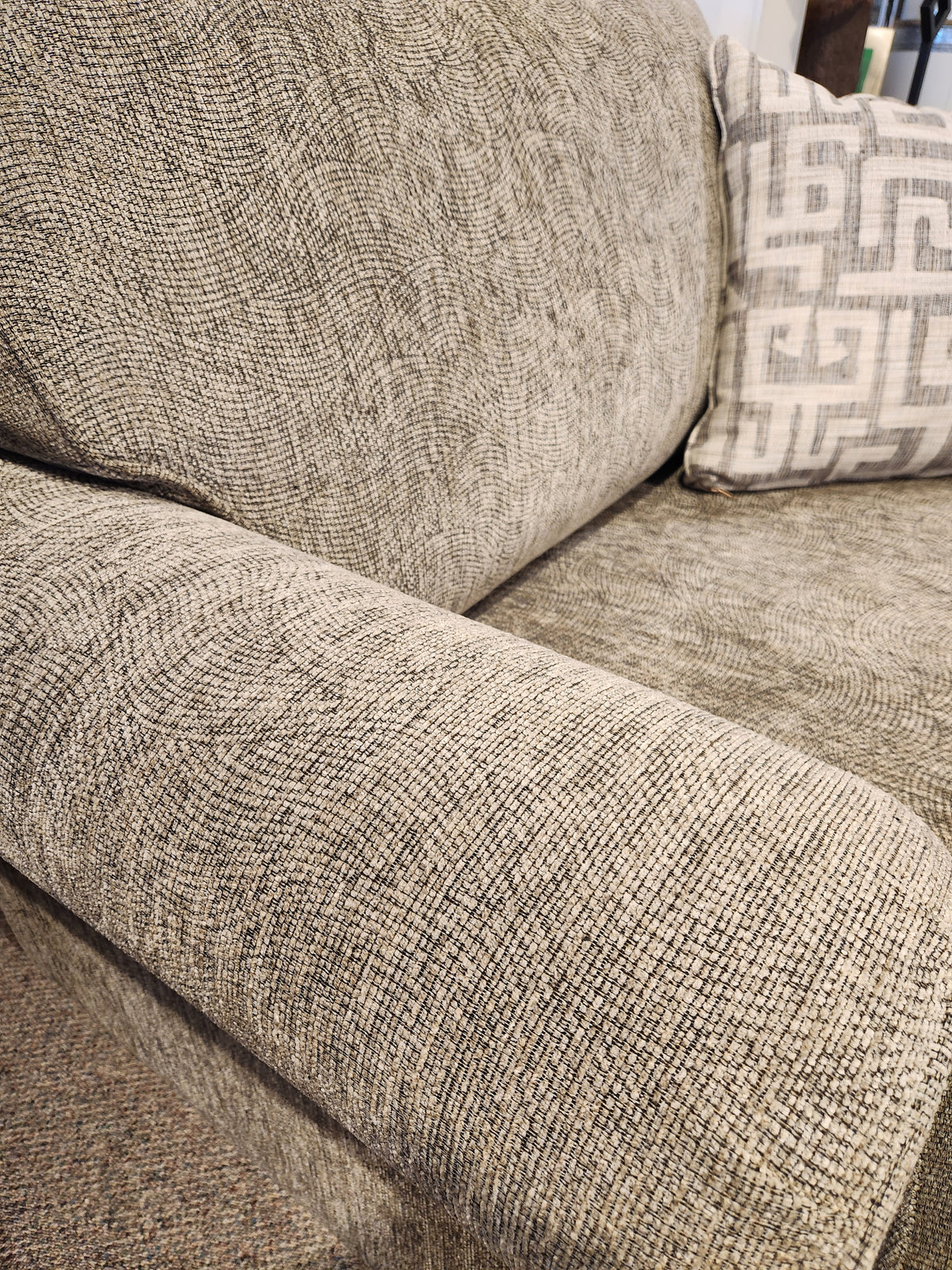 Close-up of the 2285 Chair and a Half from Decor-rest, featuring a textured gray finish with an armrest and a patterned cushion, highlighting its solid wood construction. The fabric boasts a subtle swirl design, providing both style and comfort. Proudly Canadian made for ensuring durability and timeless elegance.
