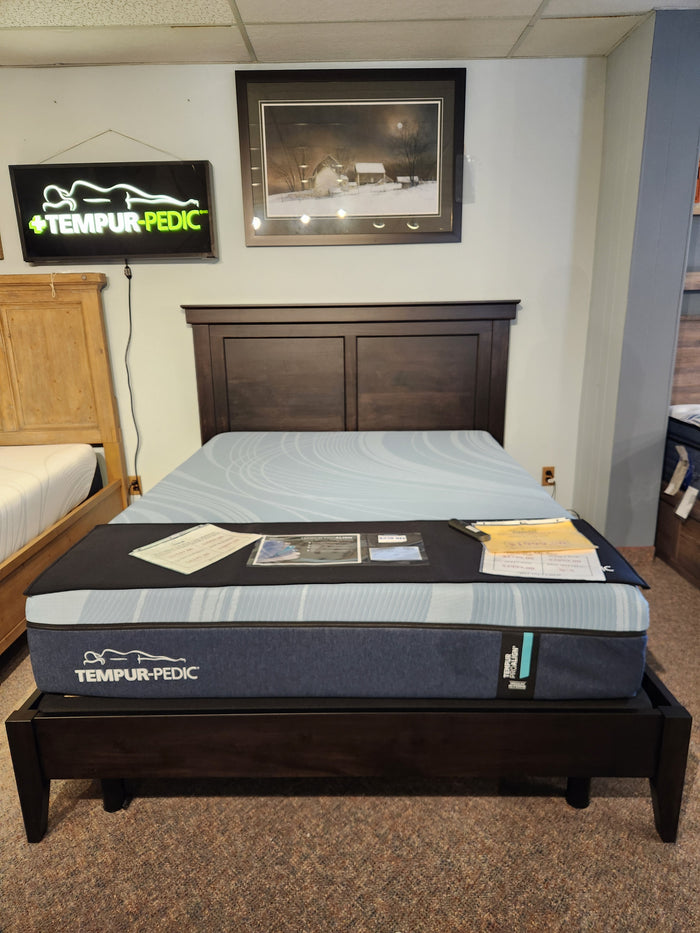 A Handstone Stockholm Queen Bed with Scandinavian design and dark wood frame, showroom brochures on top.