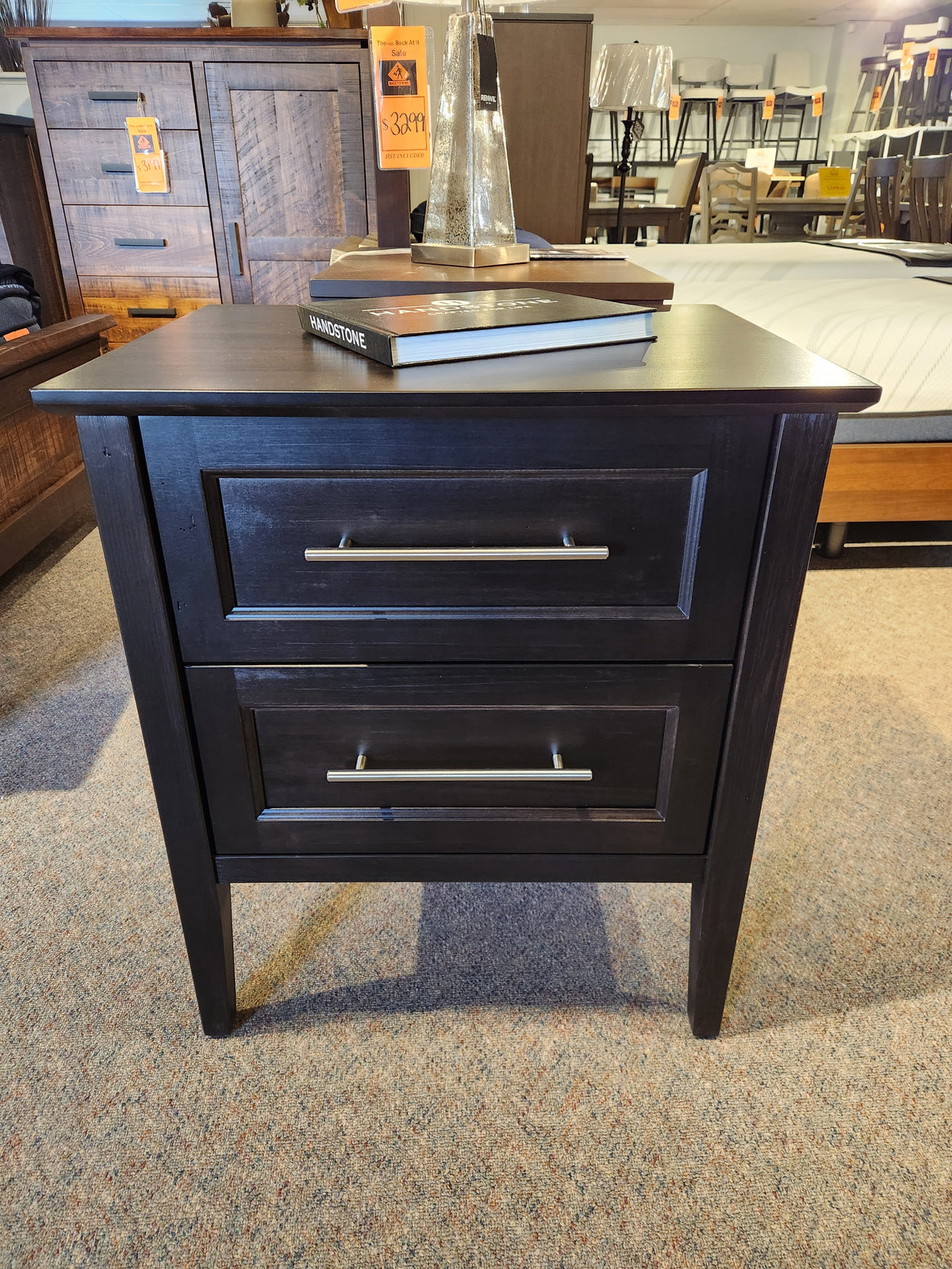 The Handstone Stockholm 2-Drawer Nightstand, featuring sleek detailing, is showcased in a store display.