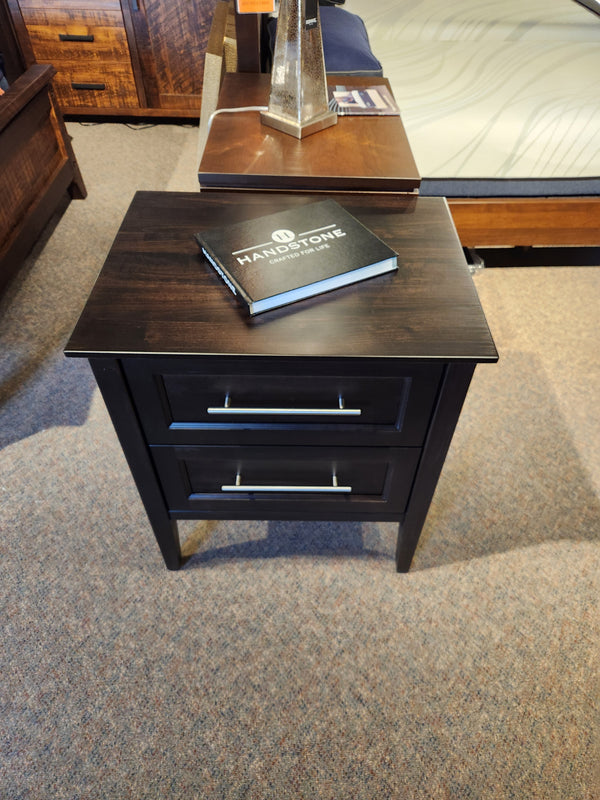 Handstone Stockholm 2-Drawer Nightstand with metal handles, displayed with a notebook in a showroom.