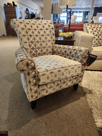 A Decor-rest 2470 Stationary Accent Chair with a striking geometric design sits proudly on the carpeted showroom floor, surrounded by other Canadian-made accent chairs and furniture pieces.