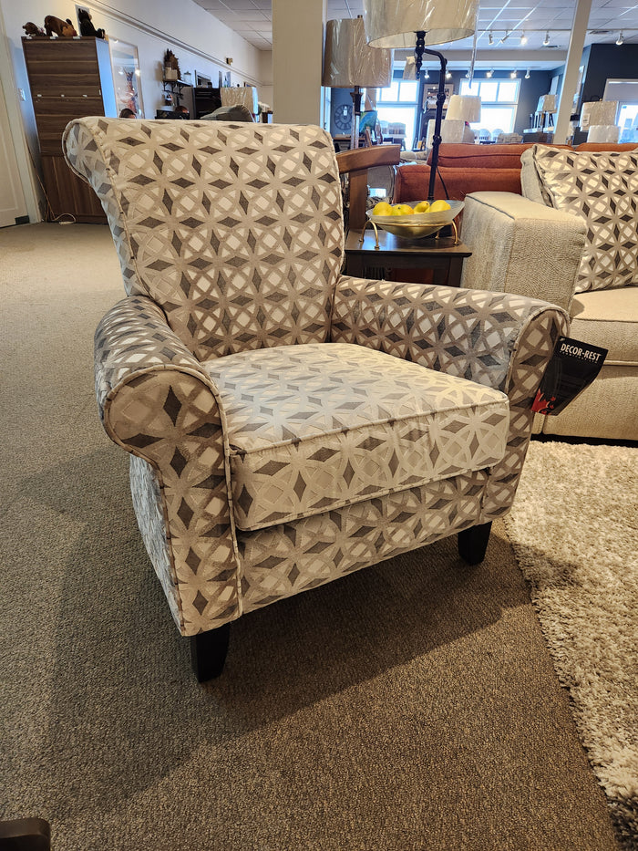A Decor-rest 2470 Stationary Accent Chair with a striking geometric design sits proudly on the carpeted showroom floor, surrounded by other Canadian-made accent chairs and furniture pieces.