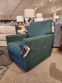 The Decor-rest 2284 Swivel Accent Chair is elegantly showcased in the furniture store showroom, complete with price tags. Its swivel glider design provides optimal support and adds a touch of modern style to any space.