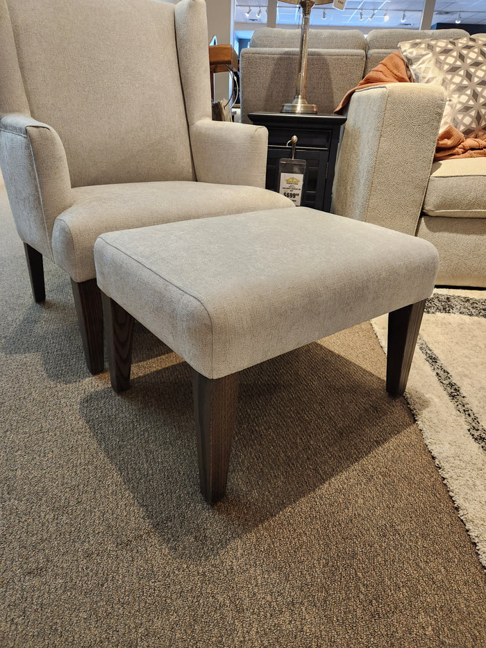 Beige armchair with rhino fabric, Belmont Ottoman by Handstone, on a carpeted showroom floor.
